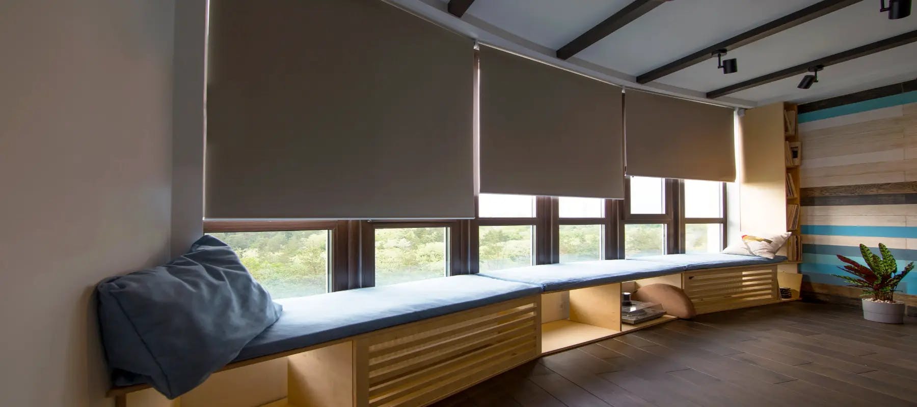 3 blinds rolled up in ascending order, letting in sunshine in the room and on the elongated window seat